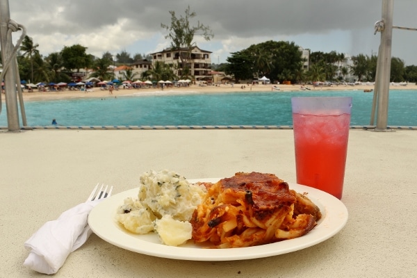 A plate of food on a boat with a beach in the background