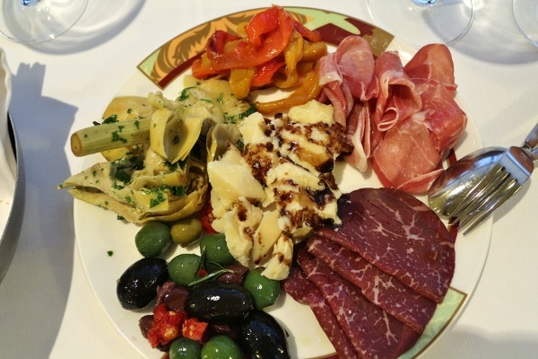 an antipasti plate with cured meats, cheese, olives, and vegetables