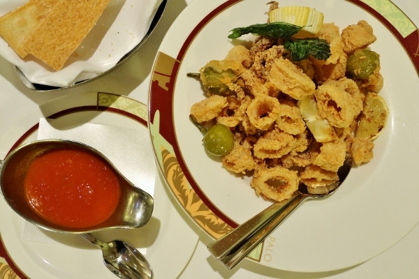 A plate of fried calamari with tomato sauce on the side