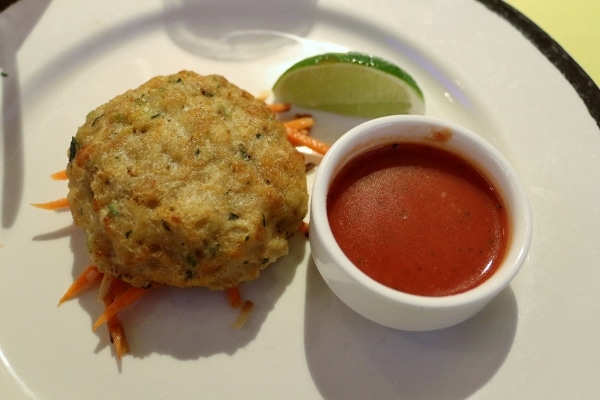 a crab cake on a plate with a side of sauce