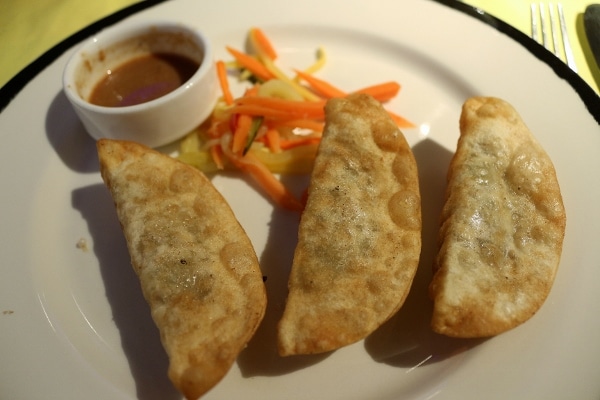 A plate of fried dumplings with dipping sauce