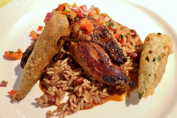 a roasted piece of chicken served over rice and peas with fried okra