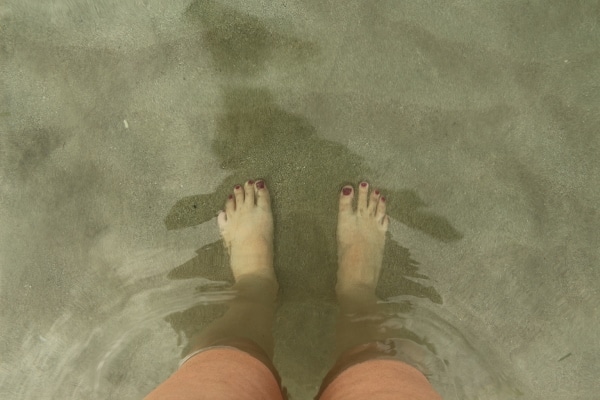 a view of bare feet through crystal clear water on a Caribbean beach