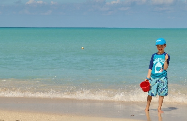 a young boy giving a thumbs on a Caribbean beach