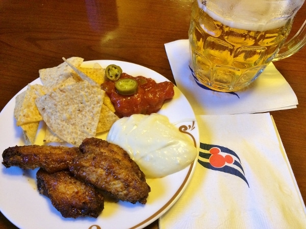 chicken wings, chips and salsa on a plate with a glass of beer on the side