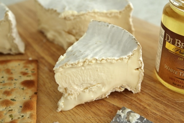 A closeup of a wedge of Camembert cheese on a wooden board