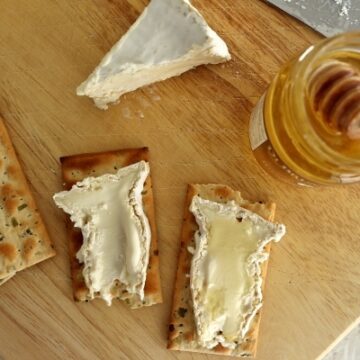 overhead view of two slices of Camembert cheese on crackers with honey