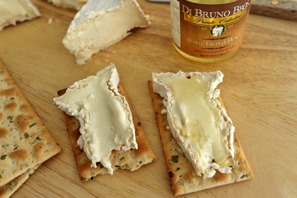 a closeup of two slices of Camembert cheese on crackers with white truffle honey
