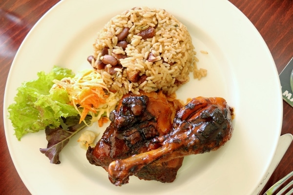 A plate of jerk chicken with rice and peas