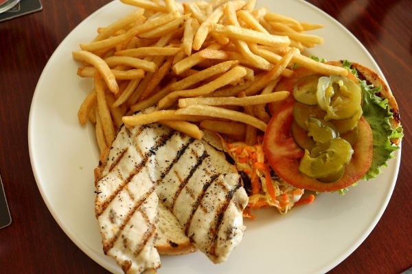 a grilled chicken sandwich on a plate with fries