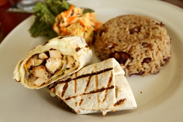 a grilled chicken wrap with rice and peas and salad on the side