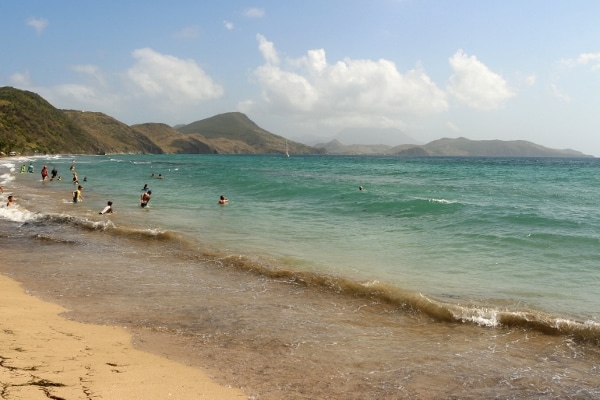 A group of people on a beach with mountains in the distance