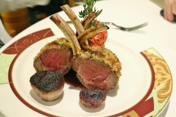 rack of lamb served with charred onions on a plate