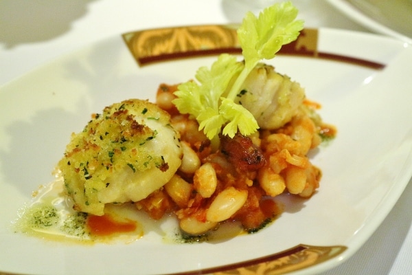 a plate of scallops served over white beans