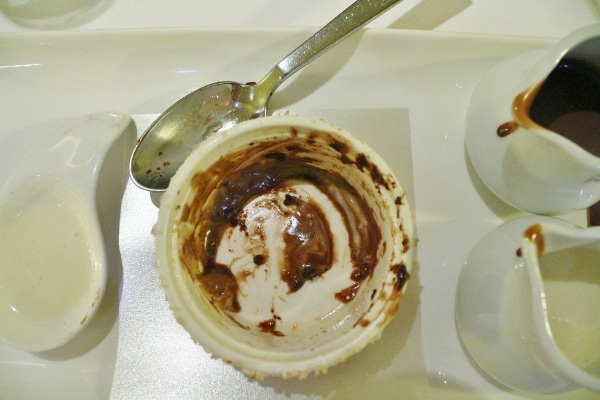 an empty ramekin with chocolate residue leftover from a chocolate souffle