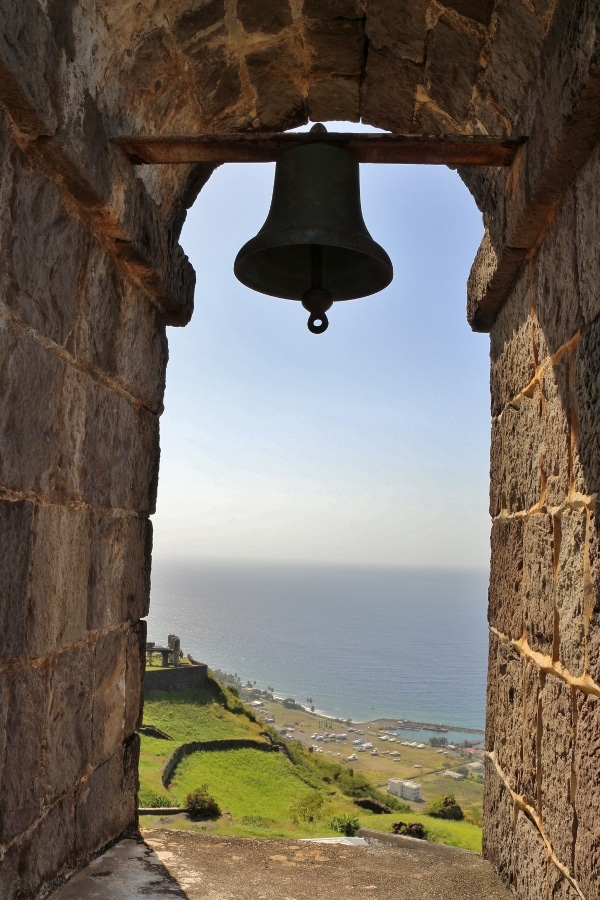 view of the shore looking out through a stone window opening with a bell
