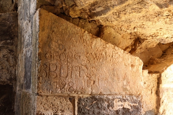 carvings of names and dates on a stone wall