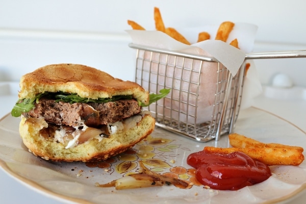 a half-eaten burger with ketchup and fries on a plate