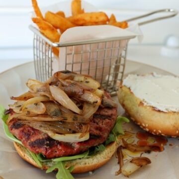 a burger with shallots and goat cheese, and fries on a plate