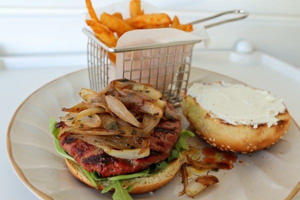 a burger with shallots and goat cheese, and fries on a plate