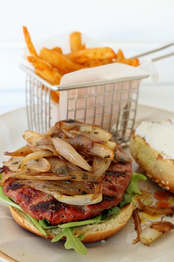 a closeup of a burger with sauteed shallots on top