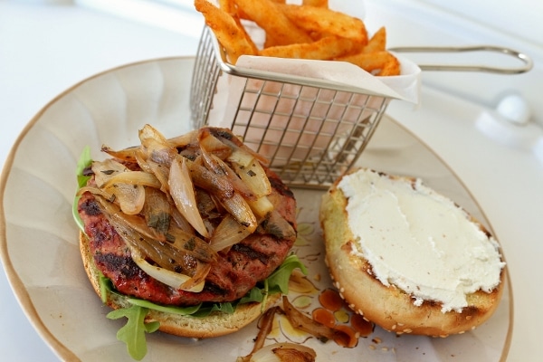 an open-faced burger with shallots and goat cheese served with fries