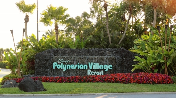 Disney\'s Polynesian Village Resort sign surrounded by flowers and palm trees