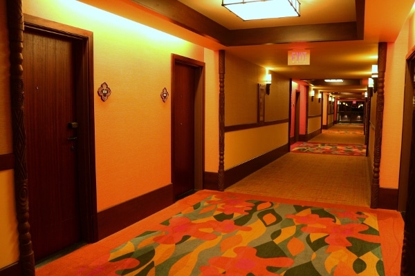a hotel hallway with tropical colored floral carpeting