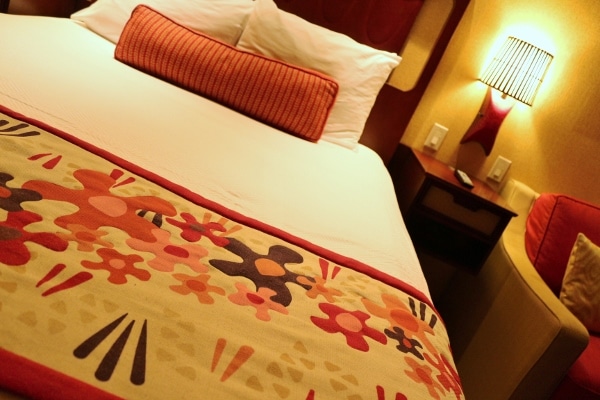 A closeup of a hotel bed with a colorful floral bed runner