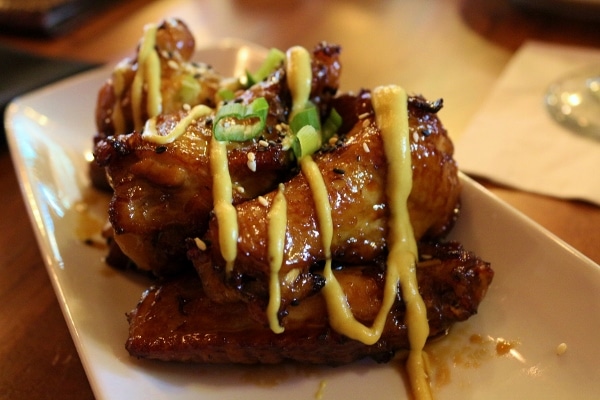 a plate of sticky fried chicken wings drizzled with sauce