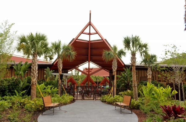 a tropical style entrance to an outdoor pool area surrounded by palm trees