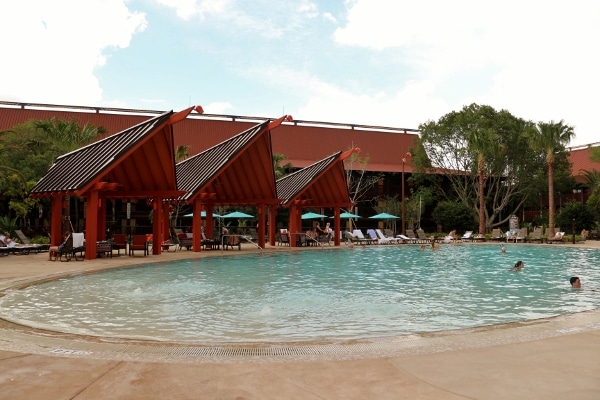 a row of cabanas next to a large swimming pool