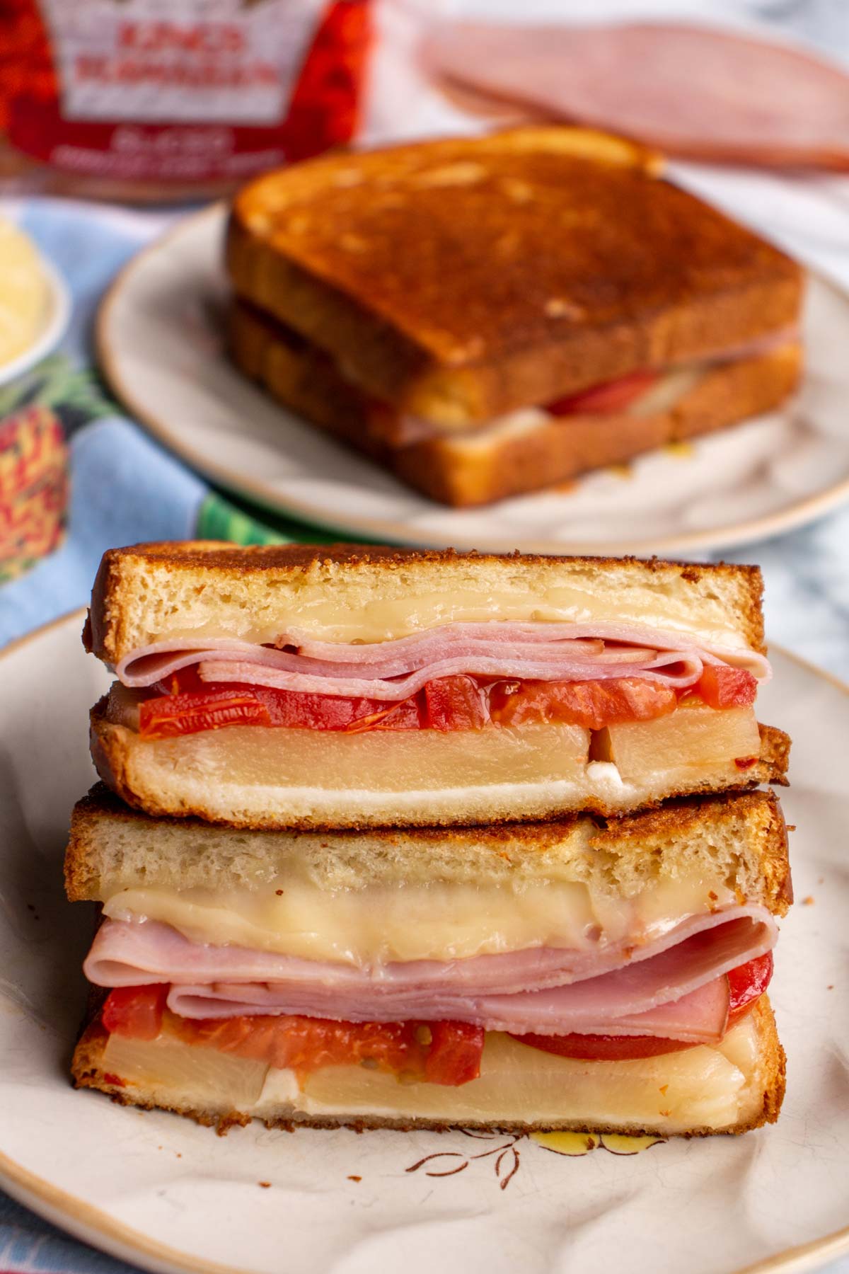 Two halves of a Hawaiian grilled cheese stacked on top of each other on a plate.