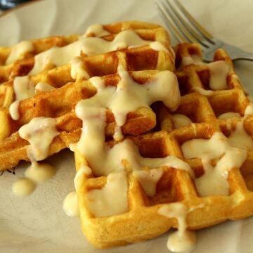 a plate of waffles with a creamy sauce drizzled over the top