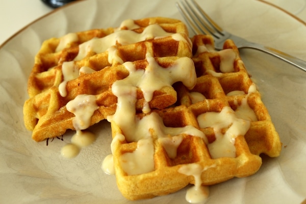 a plate of waffles with a creamy sauce drizzled over the top