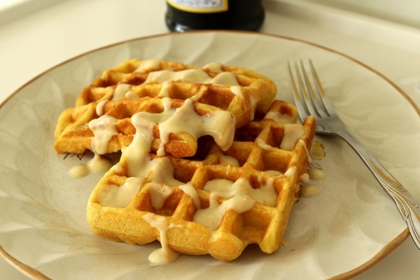 a plate of sour cream orange waffles with a creamy sauce on top