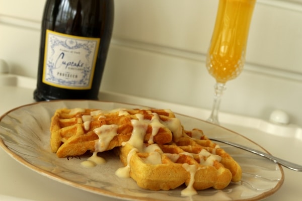 side view of a plate of waffles with a mimosa in the background