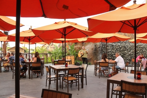 a bunch of outdoor dining tables with orange umbrellas