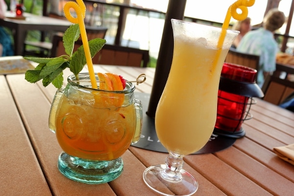 two tropical drinks with curly straws on an outdoor table