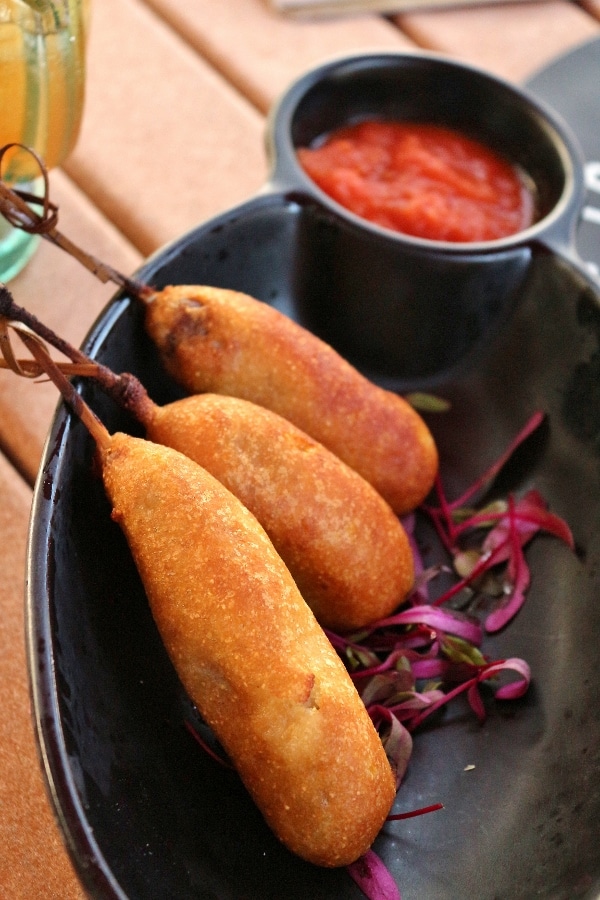 a closeup of mini corn dogs on a black plate