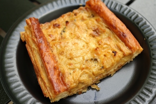 a closeup of an onion tart on a black plate