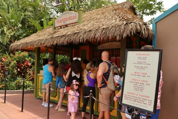 A group of people standing in line at a hut selling margaritas