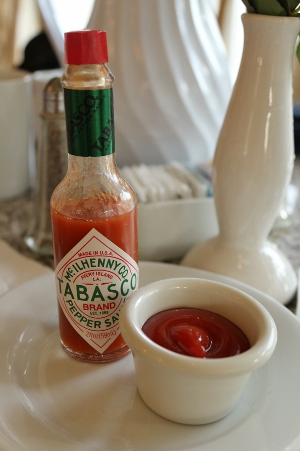 A close up of a small bottle of Tabasco sauce and a cup of ketchup