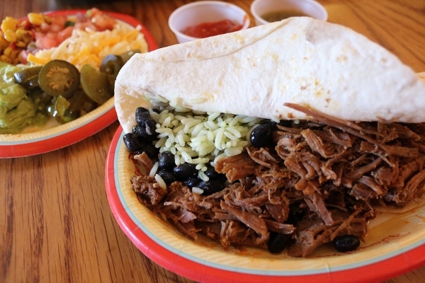 a closeup of a shredded beef, bean, and rice burrito