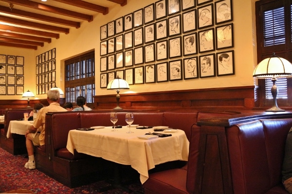 a table in a restaurant with lots of framed illustrations on the wall above