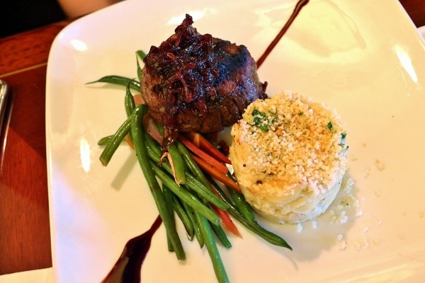 a filet mignon steak served with green beans and macaroni and cheese