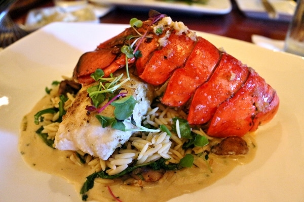 a plate of fish and lobster served over orzo pasta