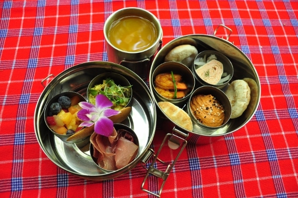 various foods in small metal dishes on a checkered tablecloth