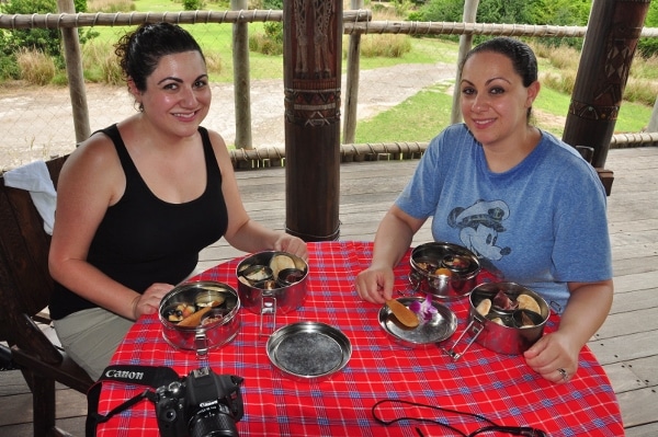 two woman posing with their food at a dining table