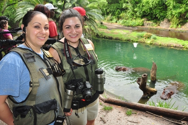 two people posing next to a hippo pool